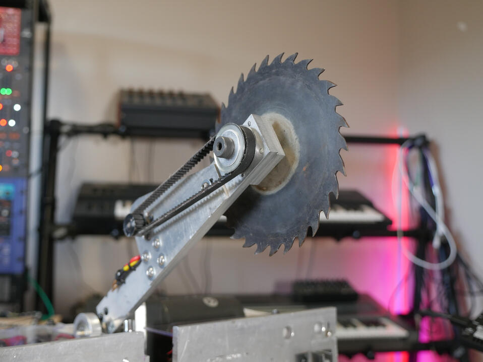 SPINNER: 2021 Larger combat robot in Makers Muse studio, metal beetleweight-class. Close up shot of a big sharp looking metal spinner blade, set on the end of a long arm.